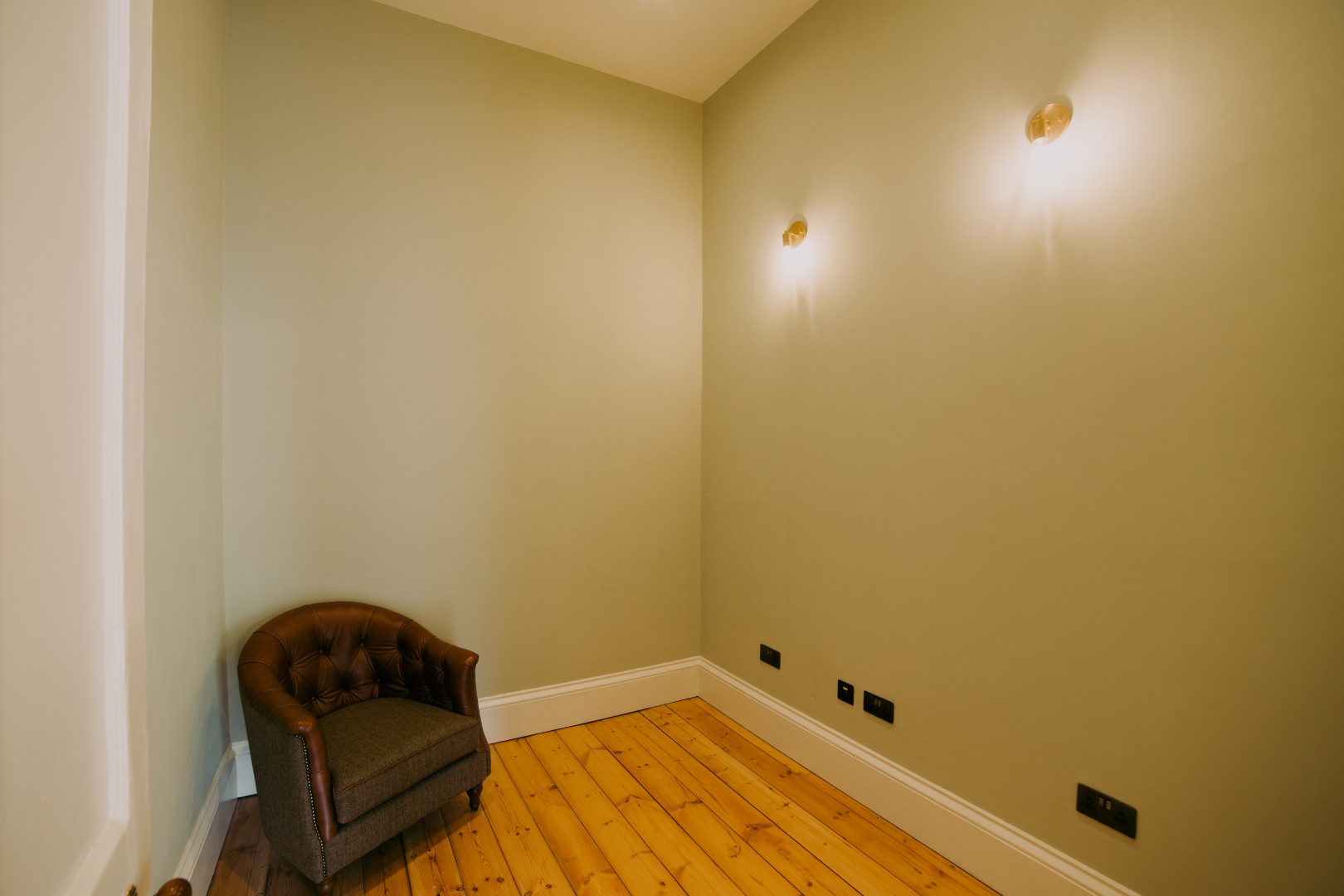 Empty room with wooden flooring and lighting.