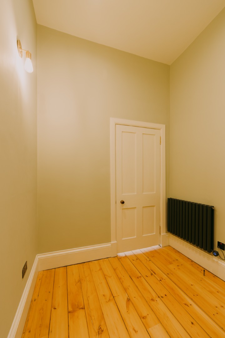 Empty room with wooden flooring and door.