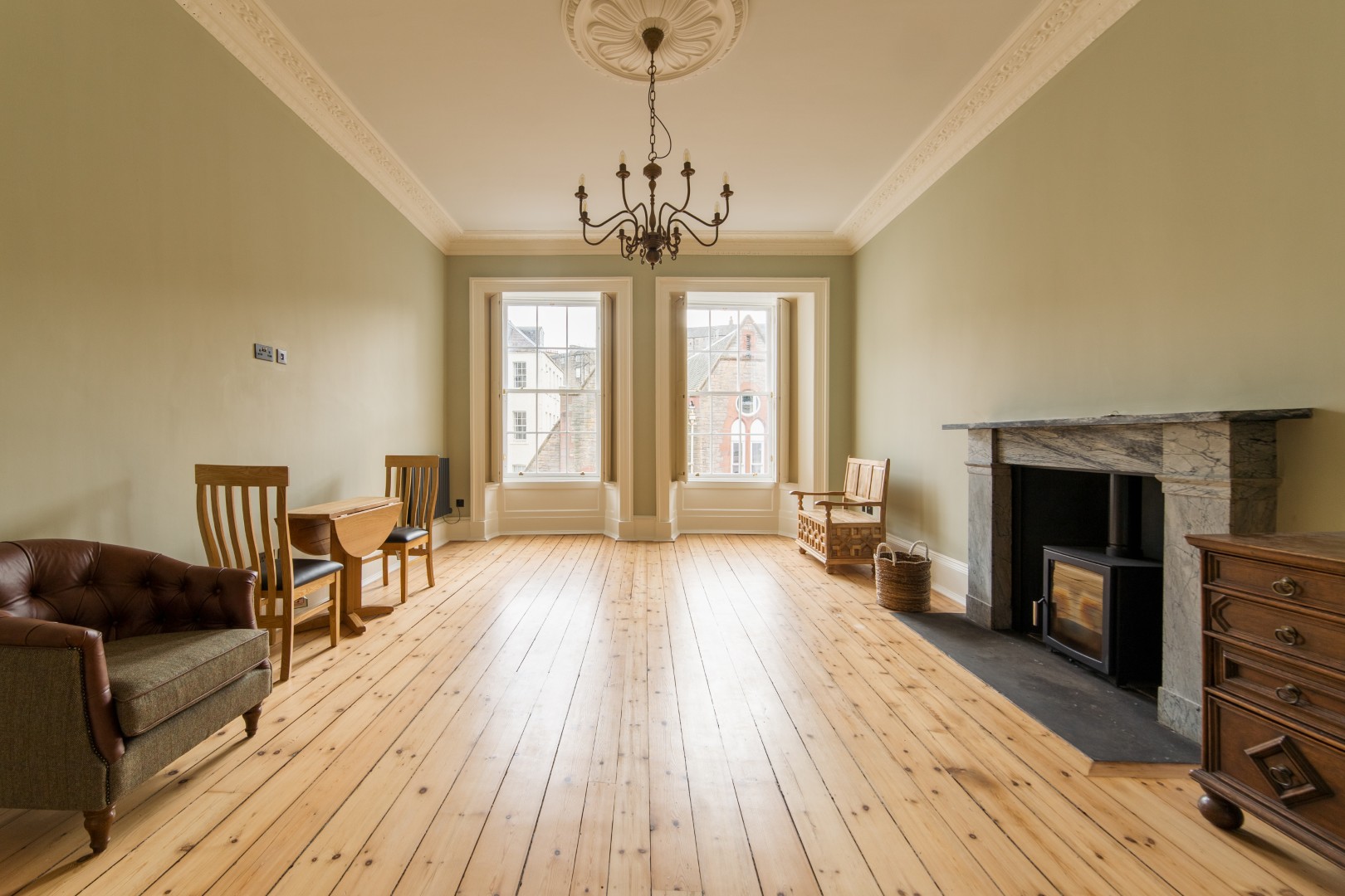 Spacious room with wooden flooring and fireplace.