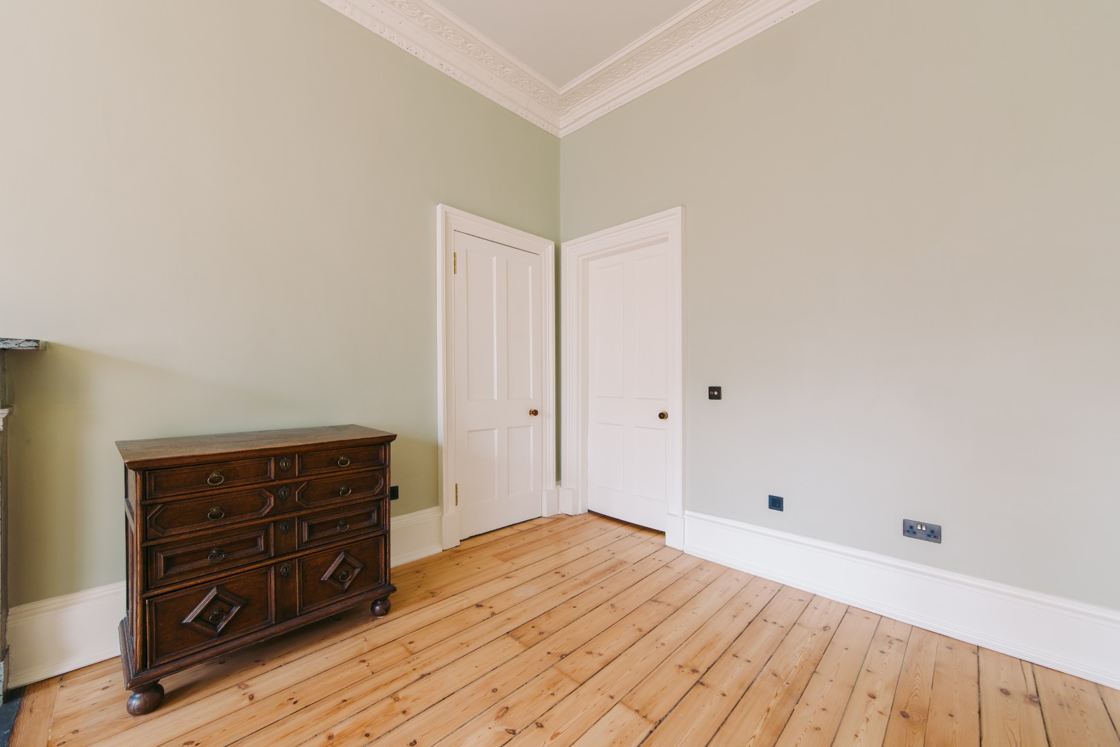 Empty room with wooden floor and doors.