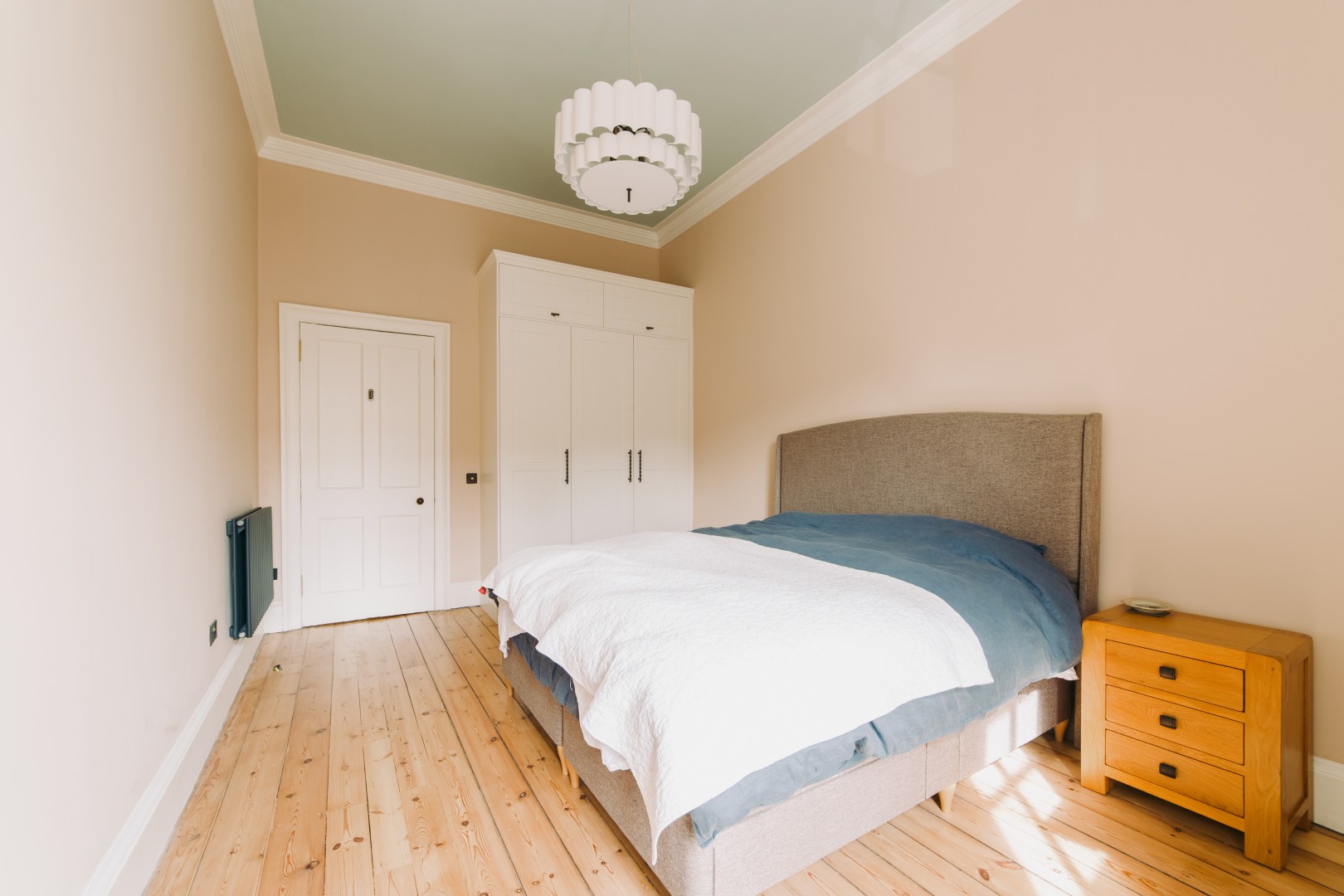 Bright, minimalist bedroom with wooden flooring.